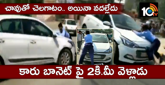 చావుతో చెలగాటం.. అయినా వదల్లేదు : కారు బానెట్ పై 2కి.మీ వెళ్లాడు చావుతో చెలగాటం.. అయినా వదల్లేదు : కారు బానెట్ పై 2కి.మీ వెళ్లాడు