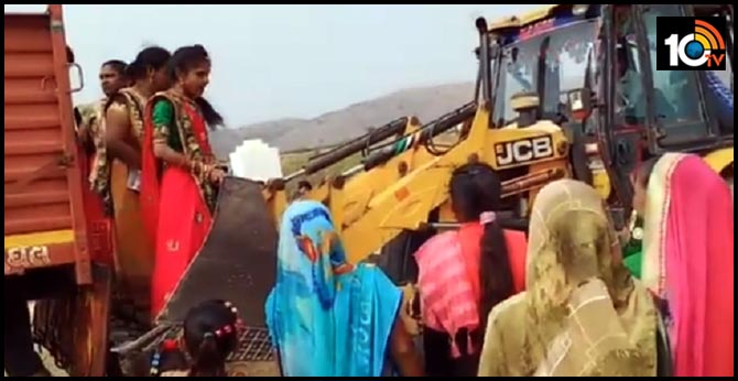 a video showing women taking help from the JCB machine to climb off a truck