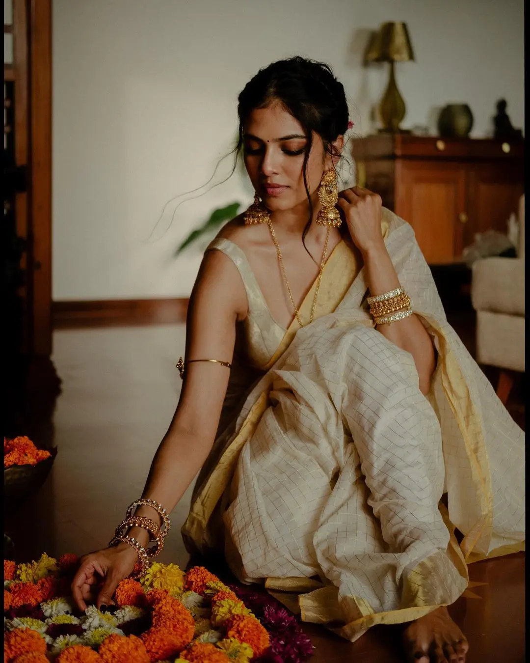 Image of An young and attractive Indian woman in white traditional sari and  red blouse and flowers is smiling while Standing at a Balcony and Posing  for the celebration of Onam/Pongal. Indian