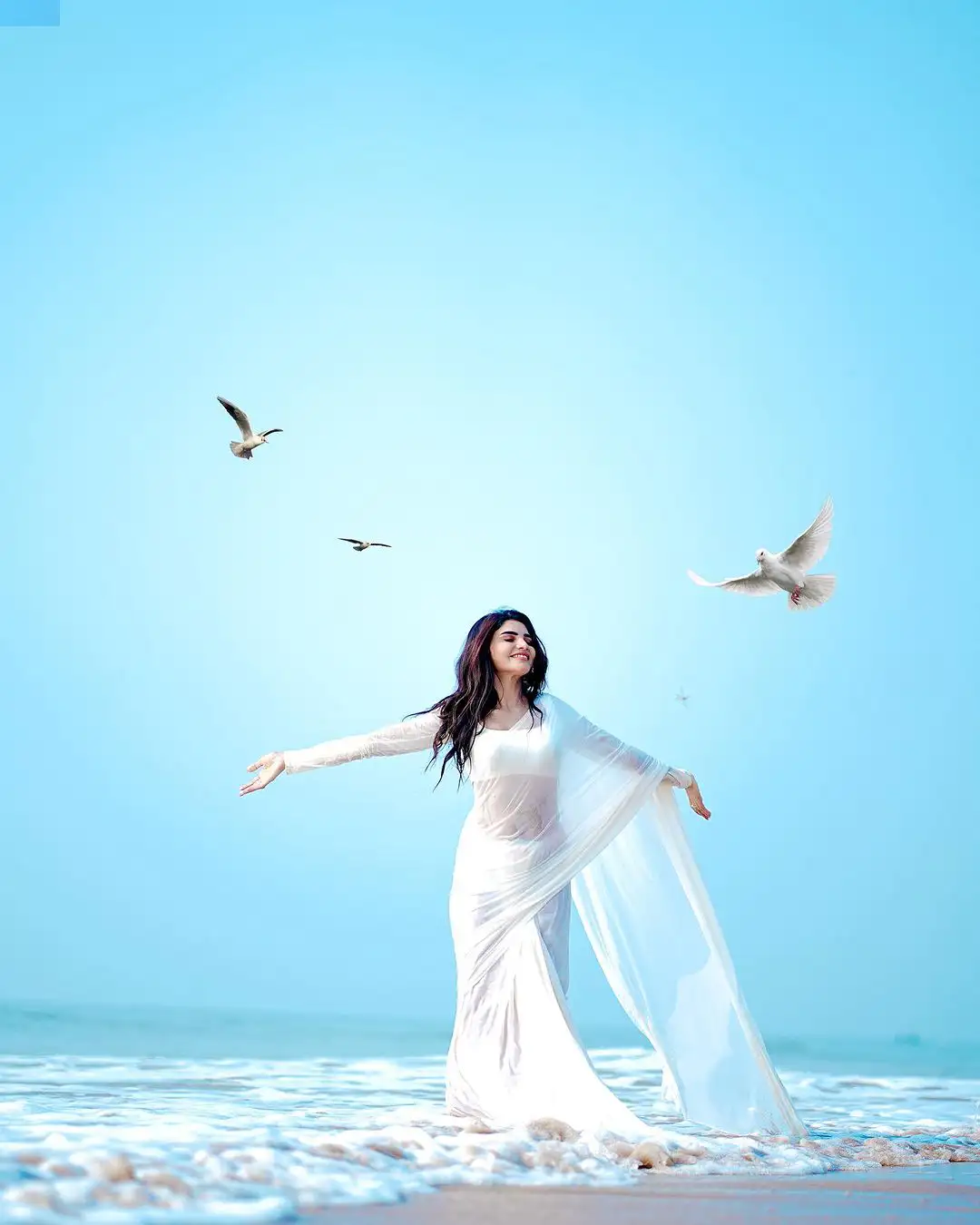 Varsha Sizzling Stills in white Saree at Beach
