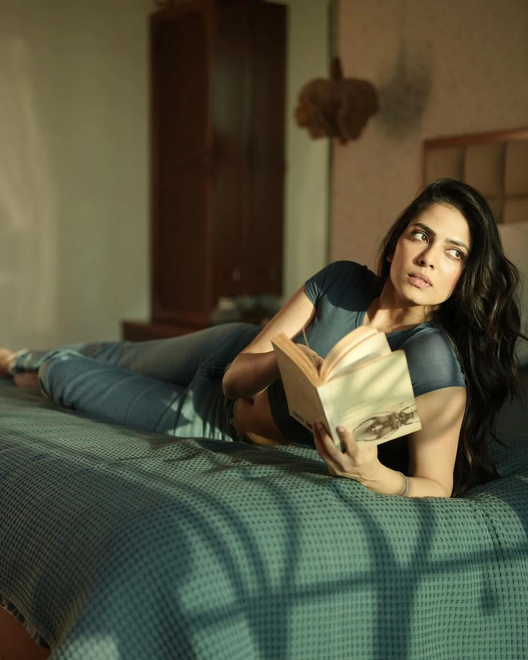 Malavika Mohanan Stills with Reading Book on Bed