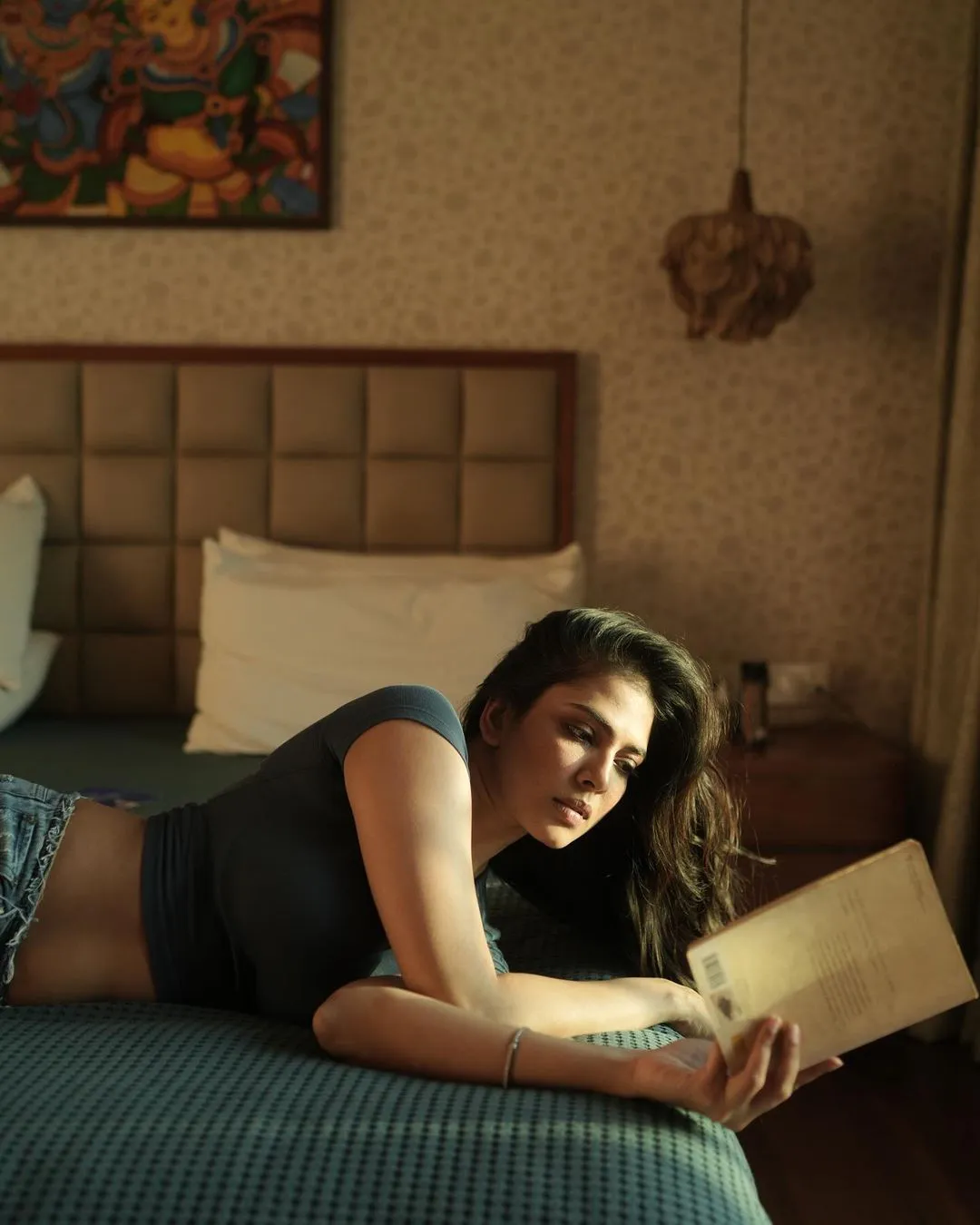 Malavika Mohanan Stills with Reading Book on Bed